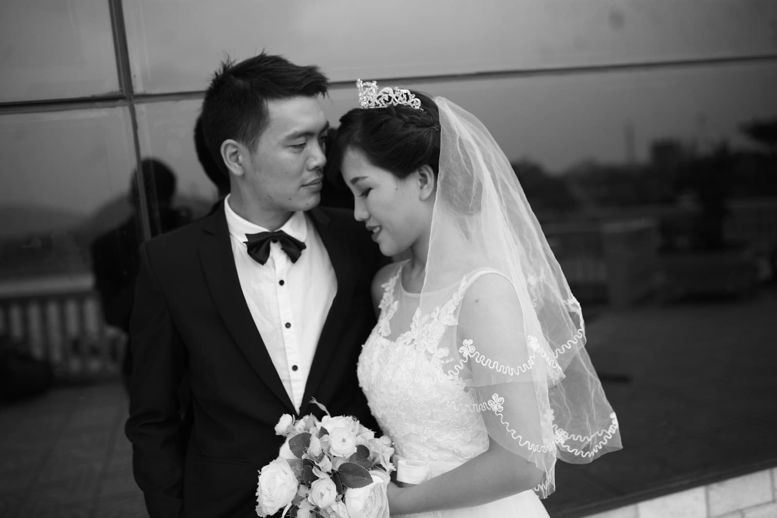 Cô dâu tựa vào chú rể, tay cầm bó hoa