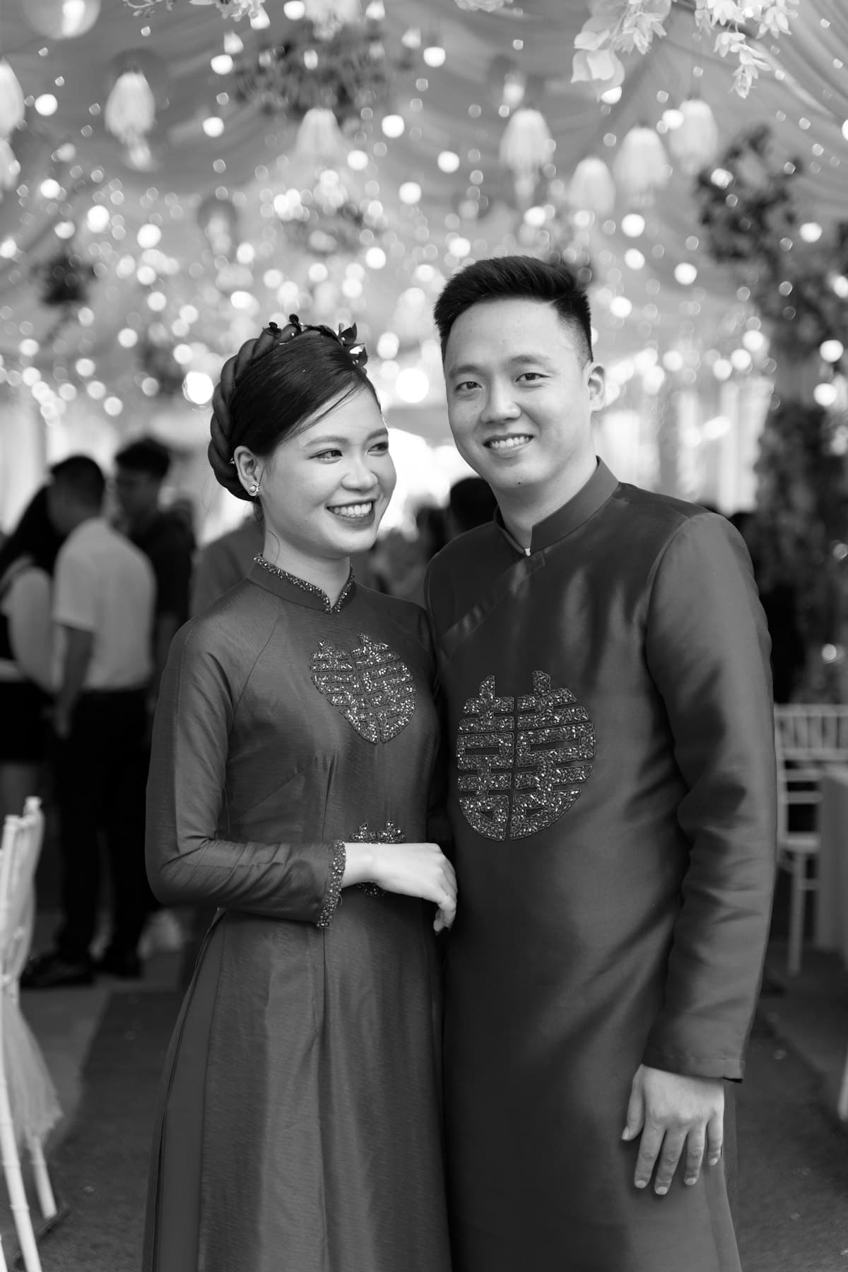 Cô dâu chú rể mặc áo dài cười giữa khách mời trong tiệc cưới